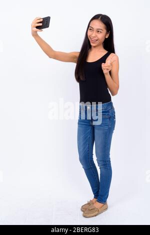 Photo complète de la jeune femme asiatique heureuse prenant selfie Banque D'Images