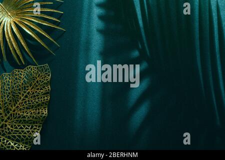 Différentes feuilles de palmier peintes en or sur fond sombre avec différentes ombres. Espace vide, espace pour le texte. Style minimaliste créatif affaires de luxe Banque D'Images