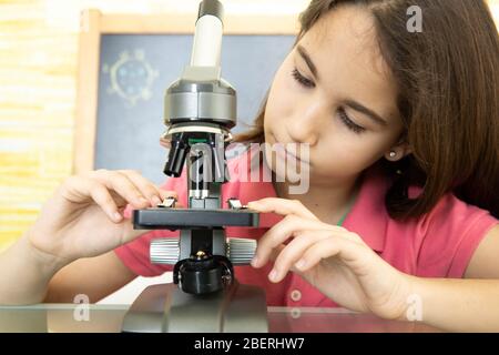 Gros plan d'une fille à la maison seule plaçant la lame sous un microscope Banque D'Images