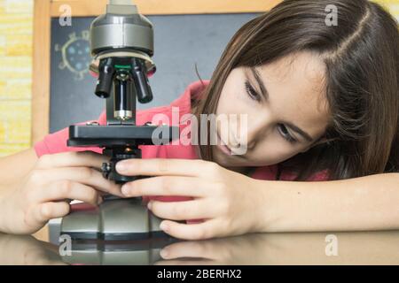 Gros plan d'une fille à la maison seule plaçant la lame sous un microscope Banque D'Images