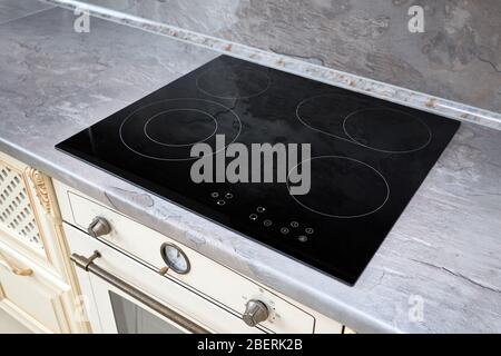 Intérieur moderne de la cuisine avec cuisinière électrique à induction noire ou cuisinière électrique avec surface en céramique avec comptoir en marbre et mur décoré avec ston Banque D'Images