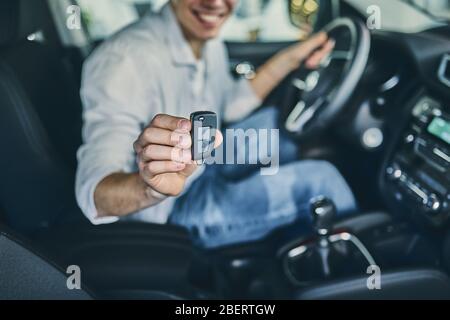 Guy appréciant une nouvelle voiture regardant l'appareil photo. Concept d'entreprise. Banque D'Images