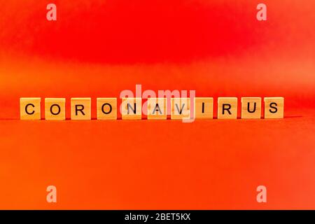 Le concept d'une pandémie et d'un virus est un mot de coronavirus composé de lettres en bois. Texte du coronavirus sur fond rouge. Covid19 Banque D'Images