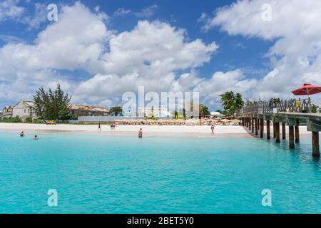 Les gens qui apprécient l'eau et la plage une journée chaude et ensoleillée au Boatyard, Bridgetown, Barbade Banque D'Images