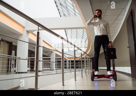 Un jeune homme d'affaires est en gyroplanche. Il parle sur le smartphone Banque D'Images