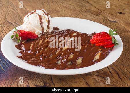 Dessert en crêpe au chocolat avec sirop, crème glacée à la fraise et à la vanille Banque D'Images