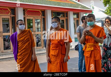 Bangkok, Thaïlande - 29 février 2020:trois moines bouddhistes au temple de bouddha inclinable, Bangkok, portant des masques de protection. Banque D'Images