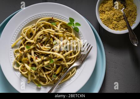 Plat de pâtes végétaliennes. Fettuccine au pesto, olives vertes au thym frais et levure nutritionnelle. Banque D'Images