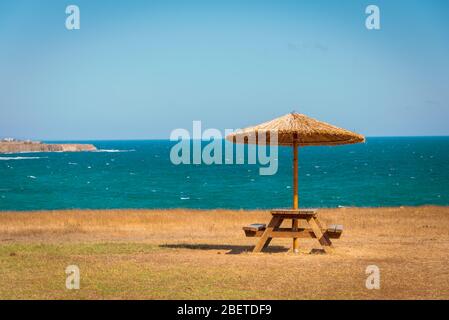 Parasol avec un banc pour contempler l'océan ondulé en arrière-plan, vibe tropical, espace de copie Banque D'Images