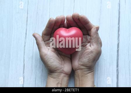 femme tenant le cœur rouge dans les mains sur table en bois . Banque D'Images