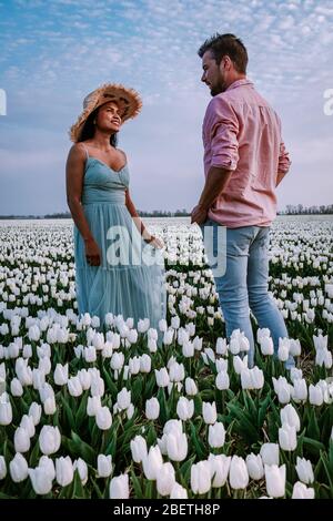 Champ de fleur de tulipe au coucher du soleil crépuscule aux Pays-Bas Noordoosstpolder Europe, heureux jeune couple hommes et femme avec robe posant dans le champ de fleur en Banque D'Images