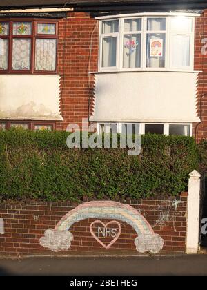 Un arc-en-ciel craché et un message de soutien et de gratitude au NHS sur le mur avant d'une maison à Sheffield Royaume-Uni également avec des arcs-en-ciel dans la fenêtre à l'étage. Banque D'Images