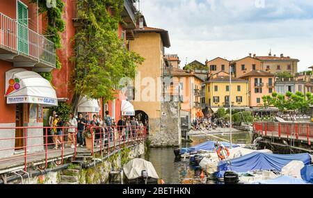 VARENNA, LAC DE CÔME, ITALIE - JUIN 2019: Les gens marchent sur la promenade étroite autour du port et des bâtiments du village de Varenna sur le lac de Côme. Banque D'Images