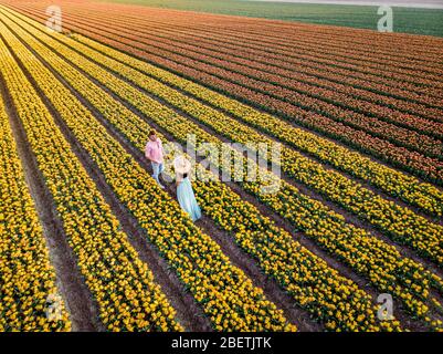 Champ de fleur de tulipe au coucher du soleil crépuscule aux Pays-Bas Noordoosstpolder Europe, heureux jeune couple hommes et femme avec robe posant dans le champ de fleur en Banque D'Images