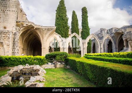 Ruines du monastère de l'abbaye de Bellapais à Kyrenia Girne avec des arches en pierre et des thujas, dans le nord de Chypre Banque D'Images