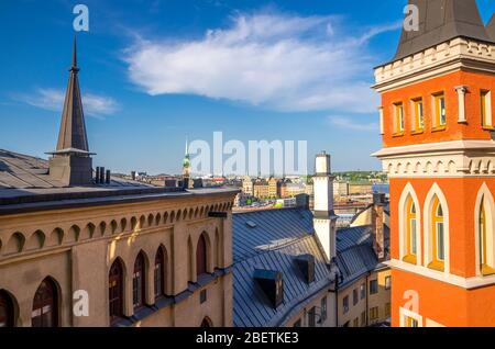 Les toits de la suède traditionnelle abritent des bâtiments avec des murs mansardés et colorés sur l'île Sodermalm Soder, des spires d'église à Gamla Stan avec bleu Banque D'Images