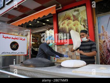 Gaza. 15 avril 2020. Les travailleurs palestiniens portant des masques de protection travaillent dans une boulangerie avec une chambre de désinfection à Gaza, le 15 avril 2020. La Palestine a déclaré mercredi que 40 nouveaux cas de la COVID-19 ont été confirmés sur son territoire, portant le nombre total à 369. Crédit: Rizek Abdeljawad/Xinhua/Alay Live News Banque D'Images