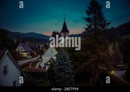 Toits d'un petit village de Bolsternang avec église et fermes dans le sud de l'Allemagne (Bade-Wurtemberg) dans les Alpes au coucher du soleil crépuscule nuit crépuscule Banque D'Images