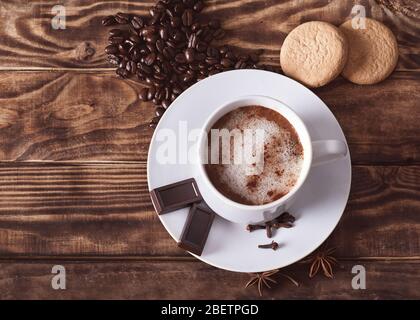 un bouchon de café avec mousse, gâteaux, grains de café en forme de coeur sur la table en bois. Plat avec pas de personnes Banque D'Images