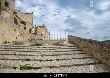 Escalier en pierre avec herbe entre l'avant près des vieux bâtiments avec ciel nuageux fond dans le centre historique Sasso Caveoso de la ville ancienne Sassi Banque D'Images