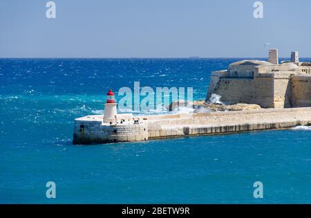 Vue sur l'entrée du port et l'ancienne Breakwater médiévale de Ricasoli est avec phare et fort Ricasoli vu de la Valette, Malte Banque D'Images