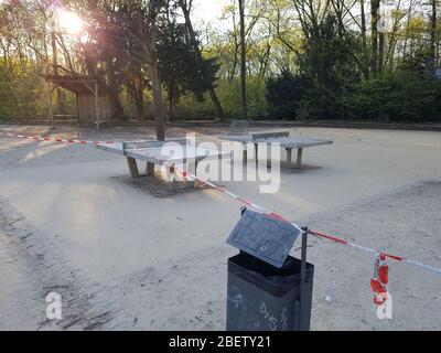 Parc public vide et abandonné avec table de ping-pong / ping-pong fermé par la barrière de police ruban et panneau d'avertissement - virus corona covid-19 Banque D'Images