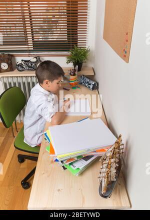 garçon de 8 ans faisant des devoirs dans sa chambre. Banque D'Images