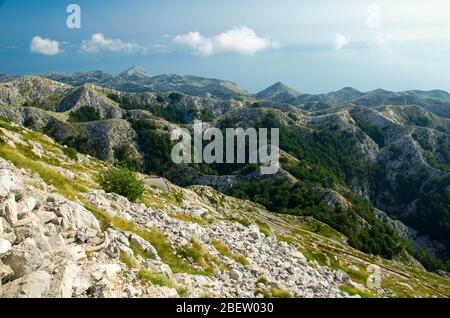 Route très sinueuse jusqu'au sommet de montagne escarpé de Sveti Jure devant les collines et les rochers de la chaîne de montagne de Biokovo avec ciel nuageux, Dalmatie, Croatie Banque D'Images