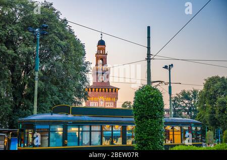 Ancien classique rétro de tramway et arbres verts en face de la tour la torre del Filarete du vieux château médiéval de Sforza Castello Sforzesco au soleil Banque D'Images