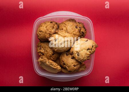 Cookies au chocolat faits maison sur un destinataire en plastique sur fond rouge Banque D'Images