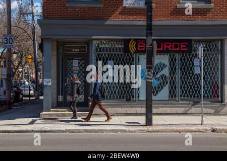 7 avril 2020 - Montréal, QC, Canada: Jeune couple passe en marchant avec un masque de visage d'écharpe sur la rue Masson, coronavirus COVID-19 pandémie, Rosemont Banque D'Images