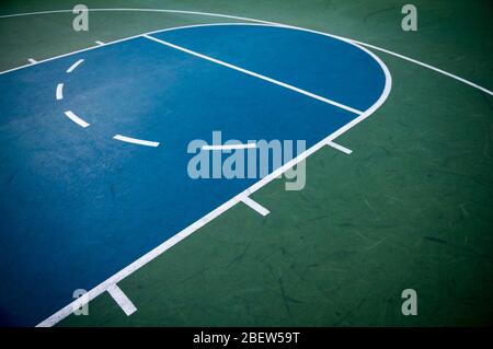 Vue rapprochée et abstraite d'un terrain de basket-ball vert et bleu bien utilisé avec des lignes blanches et des marques de éraflures Banque D'Images