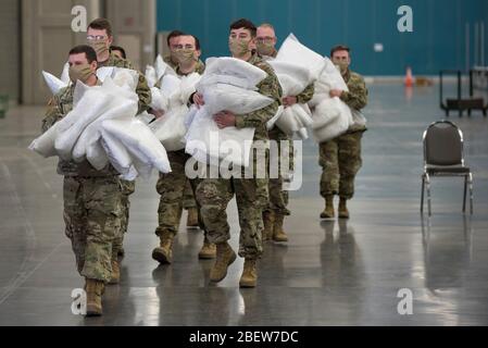 Les soldats de la Garde nationale de l'Armée du Kentucky distribuent des oreillers de lit d'hôpital pour une installation de soins de remplacement pour traiter COVID-19, patients pandémiques de coronavirus établis au Centre d'exposition et d'exposition du Kentucky le 14 avril 2020 à Louisville, Kentucky. Banque D'Images