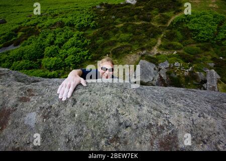 Grimpeur au sommet d'une ascension à Stanage Edge dans le Peak District Banque D'Images