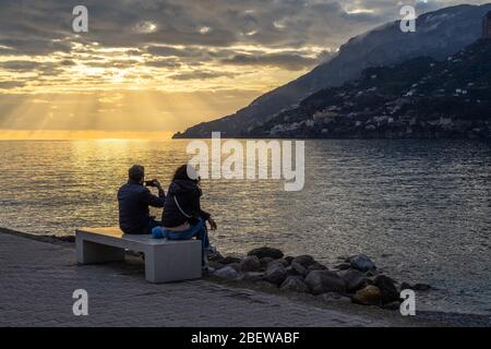 Un couple profitant d'un coucher de soleil pittoresque au bord de l'eau de Maiori sur la côte amalfitaine, Campanie, Italie Banque D'Images