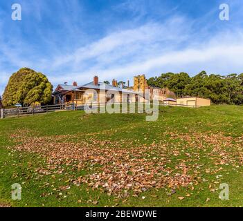 Paddle herbacé de premier plan avec feuilles tombées menant au site historique du Cottage canadien Port Arthur en Tasmanie Australie. Banque D'Images