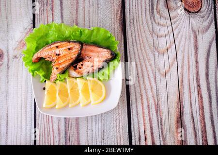 Deux steaks de saumon rose grillé sur la laitue avec des quartiers de citron. Gros plan. Banque D'Images