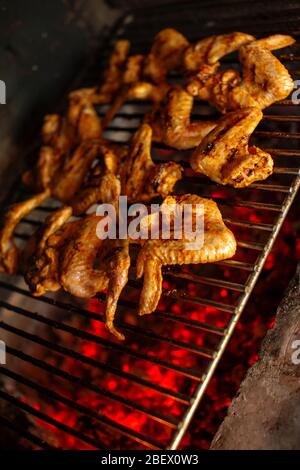 Ailes de poulet croustillantes cuisant sur un gril. Viande de poulet marinée à rôtir. Profondeur de champ peu profonde Banque D'Images