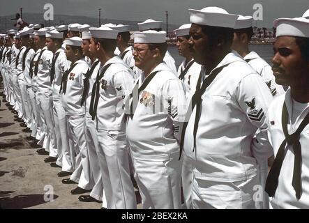 1982 - de l'équipage de la frégate lance-missiles USS LEWIS B. PULLER (FFG-23) s'élèvent à se reposer pendant le défilé pour la cérémonie de mise en service du navire. Banque D'Images