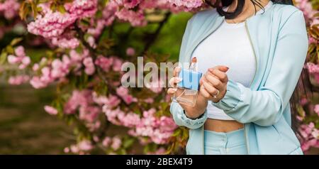 grand parfum est une chose puissante. femme avec bouteille de parfum. Parfum unisexe. Femme contenant une bouteille de parfum. Produit cosmétique avec sakura. Affiche publicitaire parfum. Lotion pour le corps avec extrait de sakura. Banque D'Images