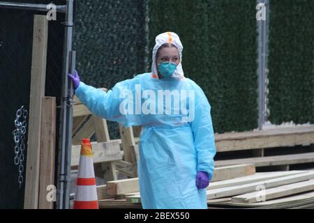New York, New York, États-Unis. 14 avril 2020. Ce jeune professionnel de la santé ouvre la porte de la plus grande morgue locale en dehors de l'hôpital Bellevue, au milieu de l'épidémie de coronavirus à New York. Entouré de grands panneaux synthétiques d'herbe, cet immense site mortuaire permet à une par une les voitures mortuaires de sortir les corps des patients avant de conduire le défunt à des maisons funéraires. Crédit: Marie le BLE/ZUMA Wire/Alay Live News Banque D'Images