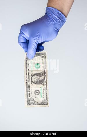 main en latex bleu avec gants et facture en dollars. Concept de crise financière coronavirus, covid-19 Banque D'Images