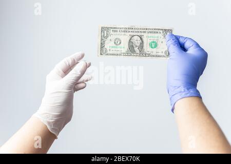 main en latex bleu avec gants et facture en dollars. Concept de crise financière coronavirus, covid-19 Banque D'Images