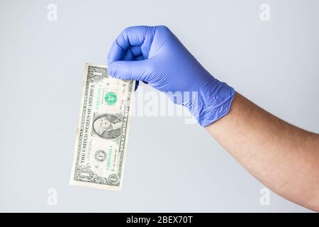 main en latex bleu avec gants et facture en dollars. Concept de crise financière coronavirus, covid-19 Banque D'Images