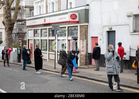 Kilburn, Londres, Royaume-Uni, 4 avril 2020 une file d'attente à l'extérieur d'un bureau de poste tandis qu'une politique de mise en place de distanciation sociale est en place pendant le virus Covid-19. Banque D'Images