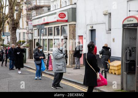 Kilburn, Londres, Royaume-Uni, 4 avril 2020 une file d'attente à l'extérieur d'un bureau de poste tandis qu'une politique de mise en place de distanciation sociale est en place pendant le virus Covid-19. Banque D'Images