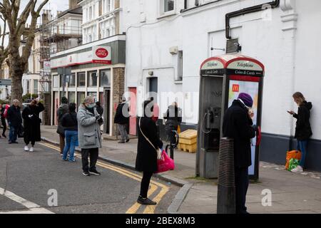 Kilburn, Londres, Royaume-Uni, 4 avril 2020 une file d'attente à l'extérieur d'un bureau de poste tandis qu'une politique de mise en place de distanciation sociale est en place pendant le virus Covid-19. Banque D'Images