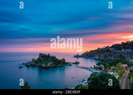 Vue imprenable sur le coucher de soleil coloré sur la magnifique baie de la réserve naturelle d'Isola Bella - un petit paradis une île sur la côte de Taormine, Sicile Banque D'Images