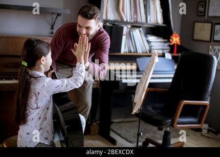 Jolie petite fille jouant de la guitare avec son professeur de musique dans l'appartement rustique Banque D'Images