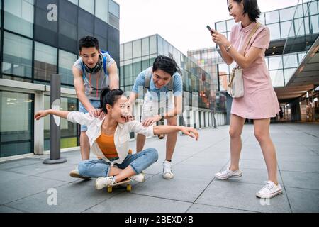 Le jeune homme pousse la femme classmate assis sur un skateboard Banque D'Images